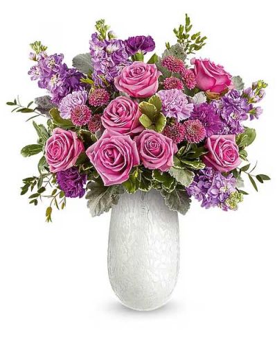 Delight Mom with the Amelia Bouquet, a graceful mix of pink and lavender blooms beautifully arranged in the Amelia Vase. This elegant art glass keepsake adds soft shimmer and a heartfelt touch to her Mother's Day.
The Amelia Bouquet is an elegant Mother's Day floral arrangement featuring lavender roses, lavender and purple carnations, lavender stock, and purple button spray chrysanthemums, accented with dusty miller, parvifolia eucalyptus, and variegated pittosporum, delivered in the Amelia Vase.
