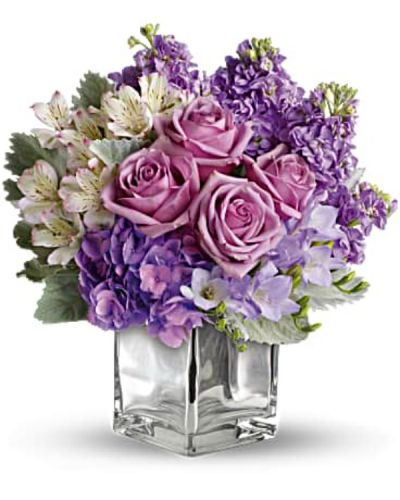 Visions of sugar plum fairies dance to life with this magical bouquet. Lush lavenders, frosty whites and silvery greens look romantic and refreshing inside a cool cube vase.
Robust roses, delicate hydrangea and feminine stock make a cool collection inside an icy, clear glass cube vase.