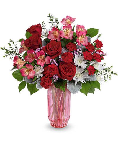 Celebrate love's radiant hues with Teleflora's Gorgeous Gem Bouquet, a stunning Valentine's Day mix of red and pink blooms in a shimmering faceted pink glass vase that sparkles with modern romance.